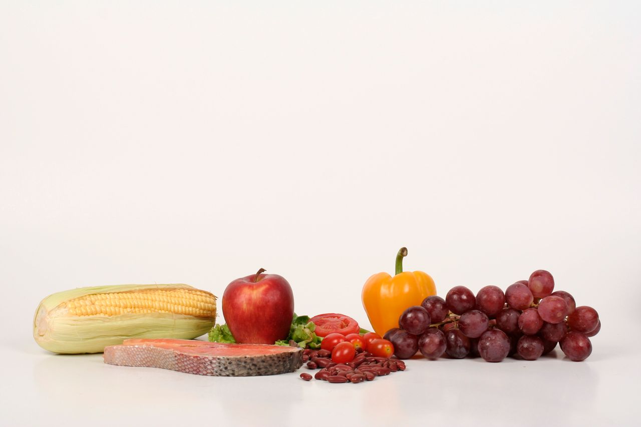 Vibrant display of fruits, vegetables, and salmon on a white background, ideal for food and health themes.