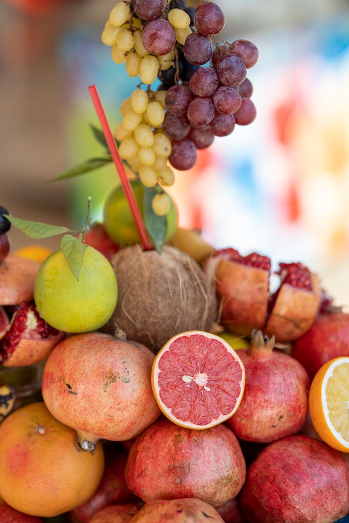A colorful display of tropical and citrus fruits, including grapes, pomegranates, and grapefruit.